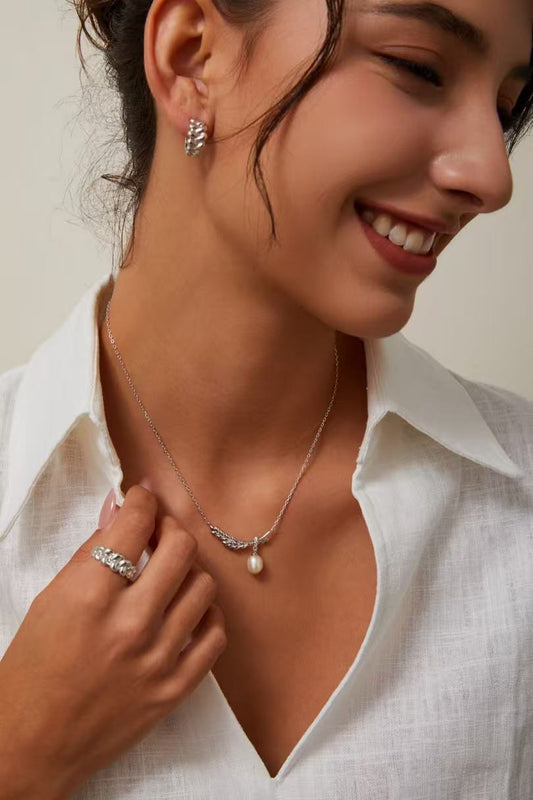 Femme portant un collier motif blé stylisé en argent 925 avec perle, gros plan sur le décolleté