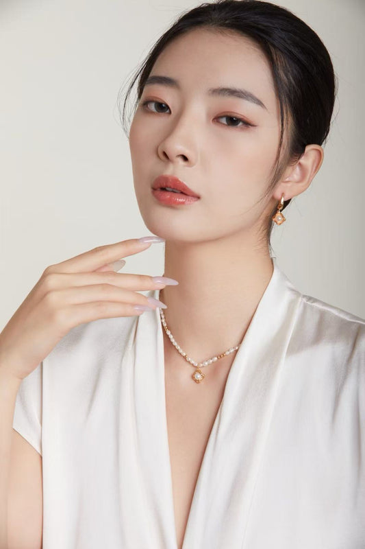 Femme portant un collier en perles naturelles avec pendentif doré vintage – bijou Éclat Royal par MeiPerle.