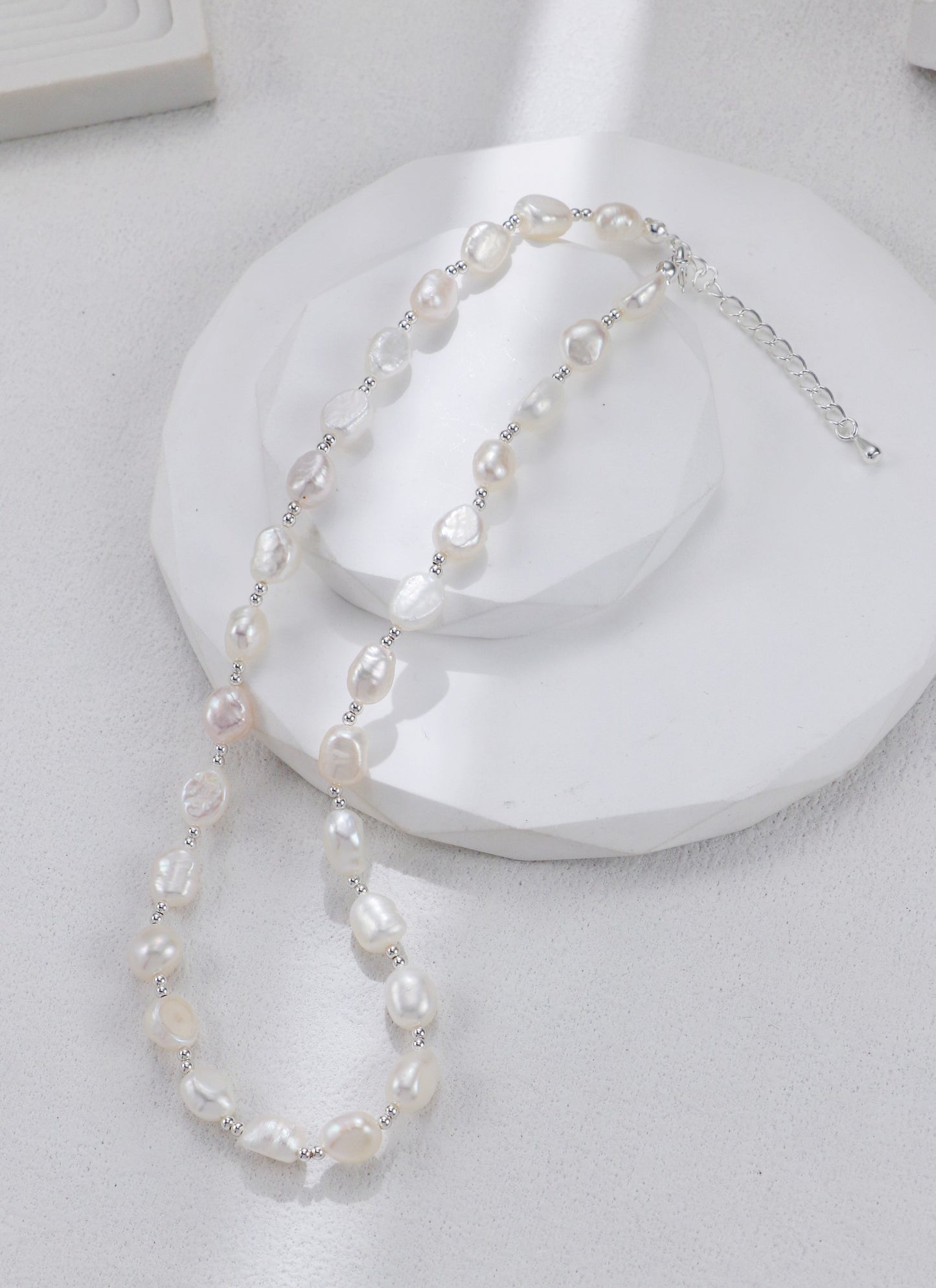 Zoom sur les perles baroques et le fermoir argenté du collier