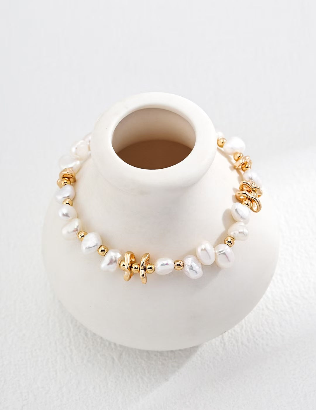 Zoom sur le bracelet Lianes d’Or exposé autour d’une tasse blanche, détails des perles et maillons