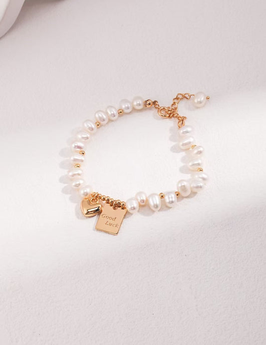 Bracelet Lueur d’Espoir en perles naturelles et pendentifs gravés dorés, posé sur fond clair