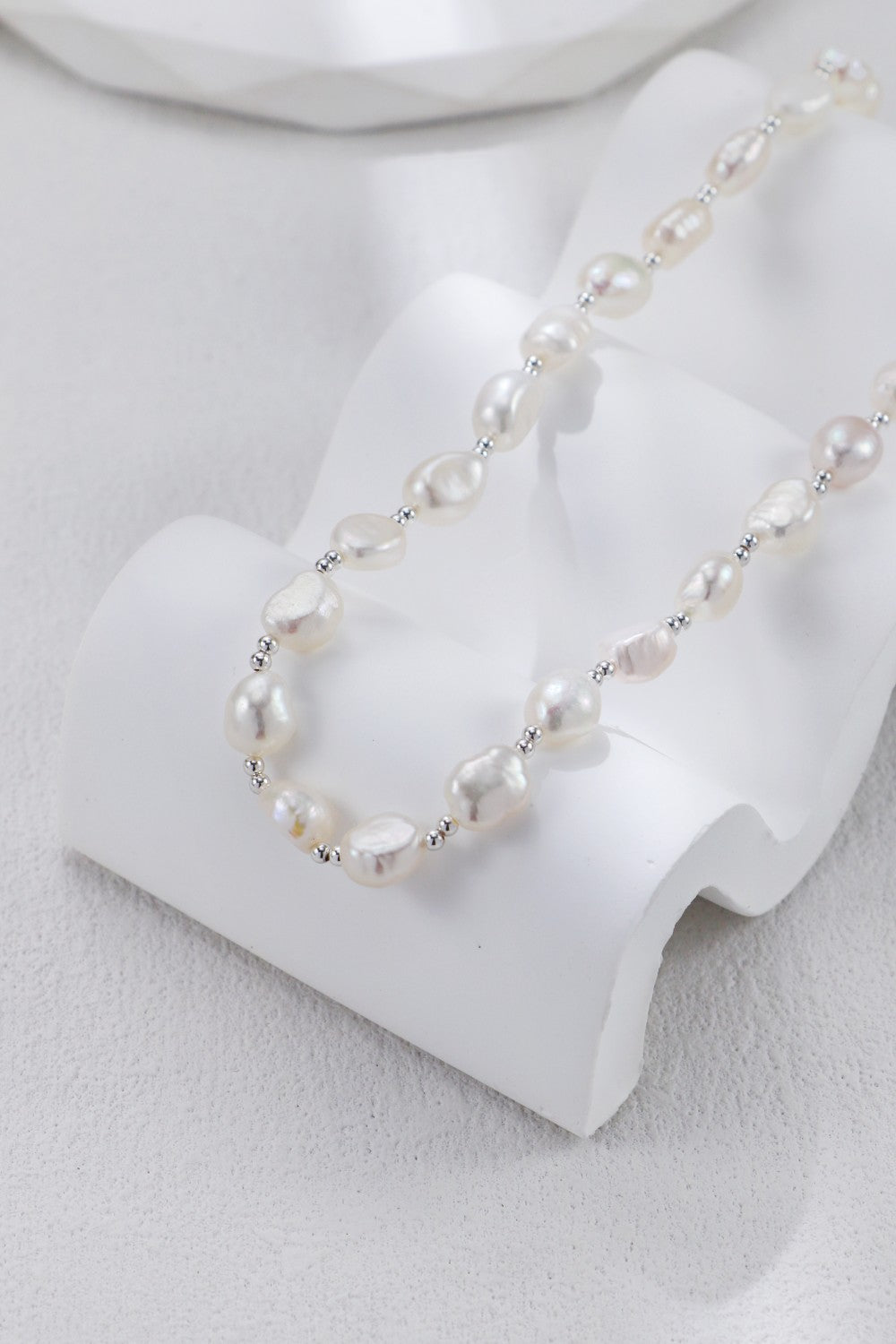 Collier perles baroques exposé sur présentoir blanc