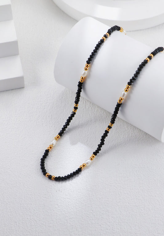 Zoom sur le collier Éclipse Dorée montrant les perles naturelles, cristaux noirs et chaînette dorée
