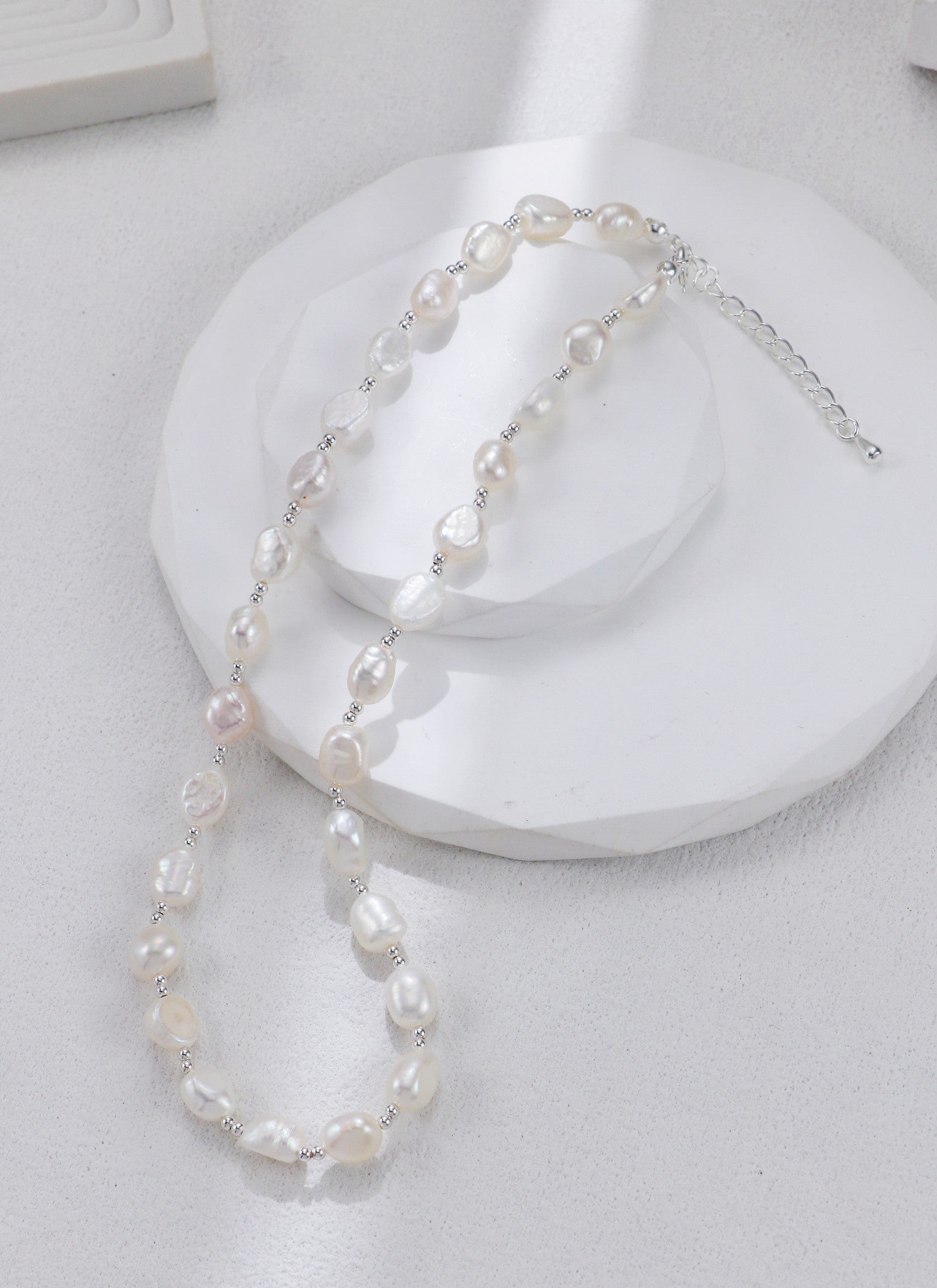 Zoom sur les perles baroques et le fermoir argenté du collier